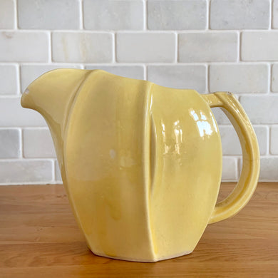 Charming vintage sunny yellow tulip pitcher. Crafted by McCoy Pottery, 1940s. This collectible pitcher is the perfect vessels to hold a charming bouquet of spring flowers or a lovely gift for an art pottery collector.

In as found vintage condition, chip to the rim and handle, tight horizontal hairline crack on handle, age-related crazing, manufacturer's glaze pops. Maker's mark.

Measures 8 1/4 x 3 1/2 x 6 inches