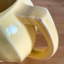 Load image into Gallery viewer, Charming vintage sunny yellow tulip pitcher. Crafted by McCoy Pottery, 1940s. This collectible pitcher is the perfect vessels to hold a charming bouquet of spring flowers or a lovely gift for an art pottery collector.

In as found vintage condition, chip to the rim and handle, tight horizontal hairline crack on handle, age-related crazing, manufacturer&#39;s glaze pops. Maker&#39;s mark.

Measures 8 1/4 x 3 1/2 x 6 inches
