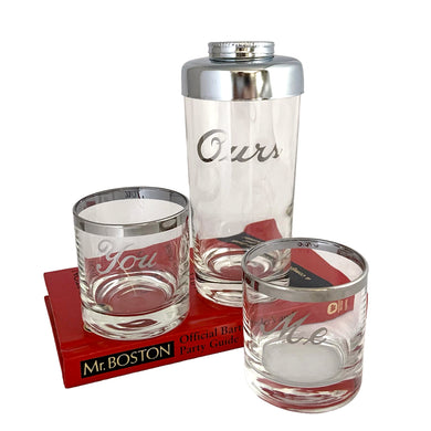 This mid-century vintage cocktail set features two silver-rimmed glasses labeled You and Me in elegant silver script, accompanied by a matching cocktail shaker marked Ours with a chrome lid. Crafted by Queens Lustreware, USA, 1950s. This set makes an ideal gift for weddings or housewarmings, celebrating togetherness with timeless style.

All pieces are in excellent vintage condition.

Shaker measures 2 3/4 x 6 inches. Capacity 12 ounces.

Glasses measure 2 1/2 x 2 3/4 inches. Capacity 4 ounces.