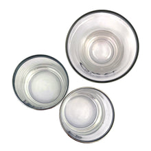 Load image into Gallery viewer, This mid-century vintage cocktail set features two silver-rimmed glasses labeled You and Me in elegant silver script, accompanied by a matching cocktail shaker marked Ours with a chrome lid. Crafted by Queens Lustreware, USA, 1950s. This set makes an ideal gift for weddings or housewarmings, celebrating togetherness with timeless style.

All pieces are in excellent vintage condition.

Shaker measures 2 3/4 x 6 inches. Capacity 12 ounces.

Glasses measure 2 1/2 x 2 3/4 inches. Capacity 4 ounces.
