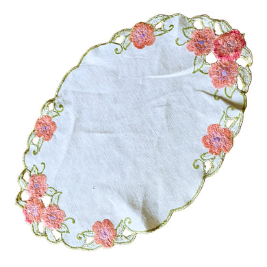 Vintage oval shaped ecru linen doily embroidered with pink flowers, green scalloped edge. In as found vintage condition. Measures 15 1/2 x 10 inches