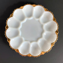 Load image into Gallery viewer, vintage milk glass serving platter features a scalloped rim finished in gold gilt,accommodates 12 deviled eggs, with an open middle that’s perfect for a small bowl or salt/pepper shakers. This lovely platter would also be perfect for serving oysters on the half shell with your fave sauce in a small bowl in the middle....just set it on top of a tray or bowl of ice. Excellent condition, free from chips/cracks. Crafted by Anchor Hocking, USA, circa 1950s. Measures 10 x 1 1/4 inches
