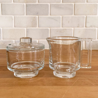 Rare vintage modernist clear glass stackable creamer and covered sugar. Designed by Joe Colombo for Arno, Italy, 1960s. Each piece has a sleek geometric design with a silhouette that makes the contents in this pressed glass appear suspended above the table surface.

Both the creamer and sugar are in excellent condition, no chips or cracks and minimal wear.

Sugar bowl measures 3 3/8 x 3 3/8 x 3 3/8 inches

Creamer measures 4 x 3 3/8 x 3 1/4 inches