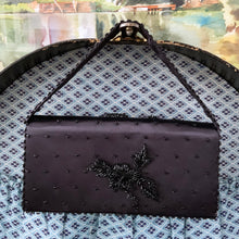 Load image into Gallery viewer, Gorgeous mid-century vintage handmade black satin evening bag/clutch covered with black seed and joined beads in a lovely floral and leaf pattern and button snap closure. May be used with or without the removable satin beaded strap. The interior is lined with black satin and has a large zippered pocket. The bag is large enough for a cell phone, credit cards/cash, compact/lipstick and comb. Produced by Contessa Francesca in Hong Kong. In overall excellent condition. Looks like it was barely used.
