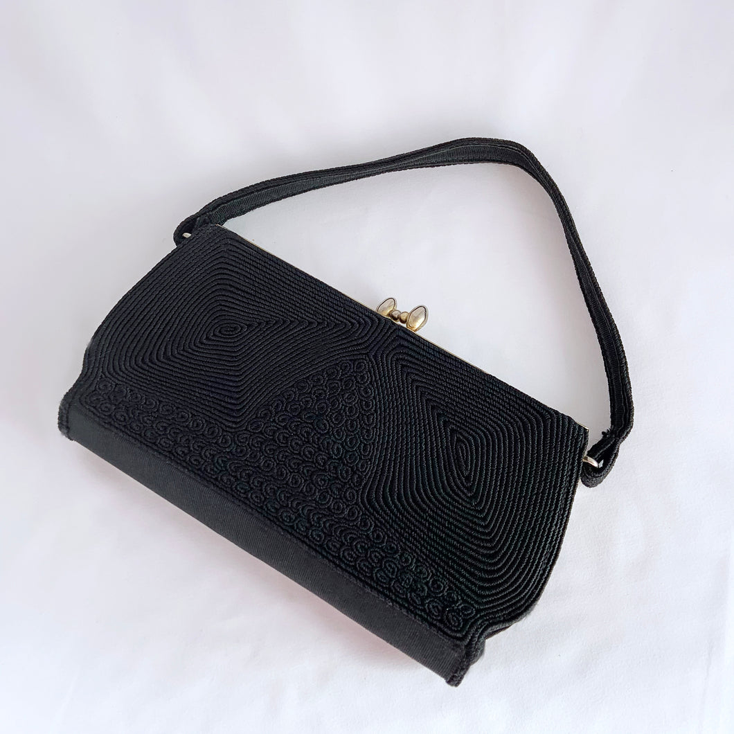 1940s art deco vintage black Corde embroidered evening bag with gold toned kiss closure. The interior is lined with black fabric having both a long brass zippered compartment and an open pocket in front of it. This bag is spacious enough to carry a full-sized cell phone, credit cards, cash, compact, lipstick, tissues. Produced by Gold Seal in the USA. Excellent vintage condition. Faded Gold Seal printed mark present on the interior. Some pin holes on the interior.