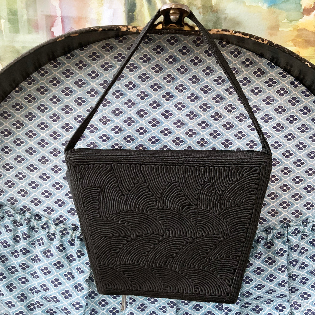 Gorgeous handmade art deco style 1940s vintage black corded evening bag with matching strap and push button closure. The interior is lined with black fabric with a small change purse. The bag is large enough for a small cell phone, credit cards/cash, compact/lipstick. Designed by Jo-Ann Original, made in Canada. A great period piece that would make an fabulous accessory. In overall excellent condition.