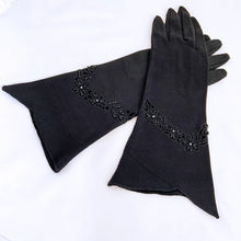 Load image into Gallery viewer, Gorgeous and elegant describes these formal black evening gloves perfectly. They have black beaded details along a cutwork band with a split cuff. The workmanship is impeccable. Circa 1950s.  In like new condition, free from stains/tears. Cotton with glass beads.  Measures 3 1/8 inches at the widest part of the hand, 4 1/2 inches at the cuff and 12 inches in length. 
