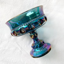 Load image into Gallery viewer, This vintage round pedestal compote in the &quot;Crown&quot; pattern is crafted of beautiful iridescent blue carnival glass. Manufactured by Colony (Indiana Glass Co.) circa 1960/70s. Serves as a stylish dish for candy or nuts. Alternatively, use it to organize items on a bathroom vanity or desk. This piece is highly versatile and adds a bit of shimmer to any decor style.    In excellent condition free from chips or cracks.  Measures 5 x 5 1/4 inches

