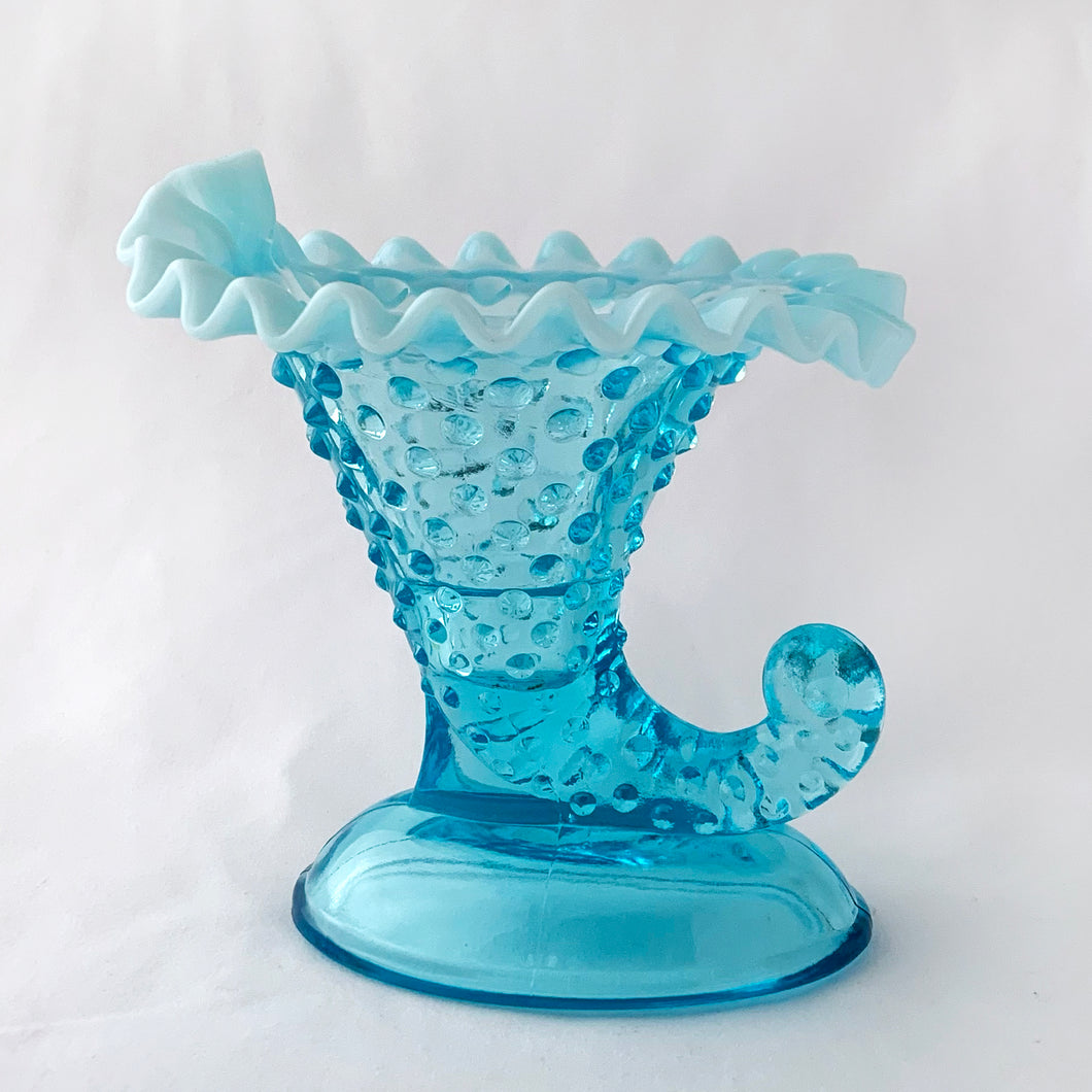 This gorgeous vintage blue hobnail cornucopia candle holder or vase has a lovely crimped opalescent edge. Produced by the Fenton Glass Co. in Williamstown, West Virginia, USA between 1940 - 1954 and 1959 - 1965.  It is perfect as a candle holder or flower vase or could even be used for make-up brushes on a vanity. The glass is a gorgeous light blue with milky opalescent rims that will brighten any room.   Unmarked and in excellent condition, no chips and no cracks.  Measures 5-1/4