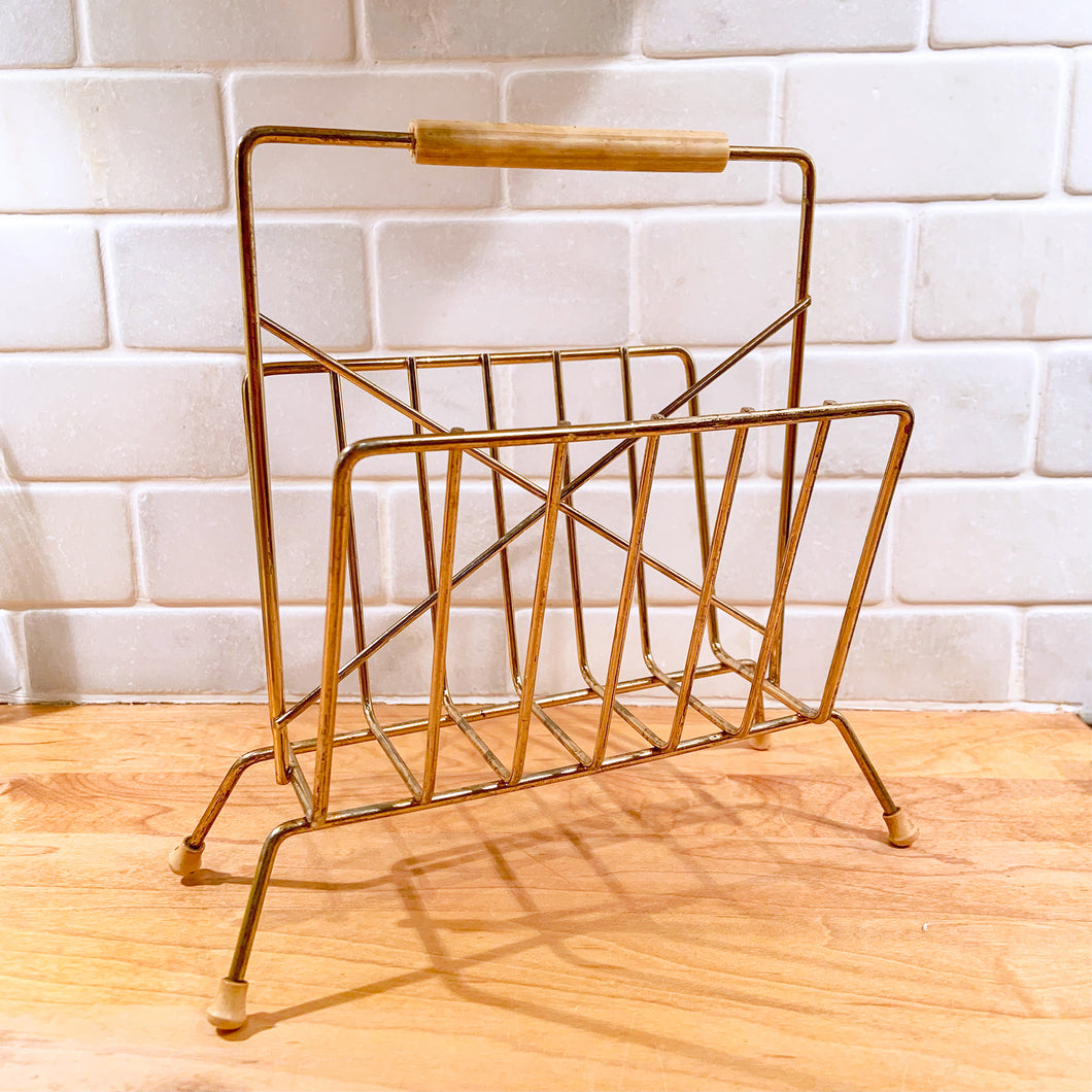 Miniature version of a vintage brass wire magazine rack/stand with wooden handle and rubber feet. Perfect to hold letters/paperwork or napkins, making it a unique piece to add to your desk or kitchen decor!  In excellent vintage condition, all welds are intact, minor oxidation to the metal.  Measures 8-1/2 x 4-3/4 x 8-1/8 inches
