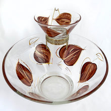 Load image into Gallery viewer, Super funky vintage chip and dip set painted on the outside with brown leaves and gold accents. Perfect for your next party, movie night, game night or get-together. There is no obvious wear on the glass. The small bowl fits nicely in the gold coloured metal hanger which secures it onto the large bowl. Produced by Anchor Hocking, USA, circa 1960s.  Excellent over condition, no chips or cracks.  Measurements: large bowl 9 1/2 x 4 inches | small bowl 5 x 2 1/4 inches
