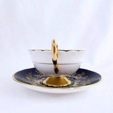Load image into Gallery viewer, This vintage &quot;Cairo&quot; bone china teacup and saucer is absolutely stunning! Both the cup and saucer are glazed in cobalt blue and  overlaid with gold gilt birds, butterflies and florals with a white exterior and gold gilt trim. Produced by Coalport, England, circa 1950.  In good condition, free from chips, cracks and repairs.  Teacup measures 4&quot; x 2-1/8&quot;  | Saucer measures 5-3/4&quot;
