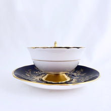 Load image into Gallery viewer, This vintage &quot;Cairo&quot; bone china teacup and saucer is absolutely stunning! Both the cup and saucer are glazed in cobalt blue and  overlaid with gold gilt birds, butterflies and florals with a white exterior and gold gilt trim. Produced by Coalport, England, circa 1950.  In good condition, free from chips, cracks and repairs.  Teacup measures 4&quot; x 2-1/8&quot;  | Saucer measures 5-3/4&quot;
