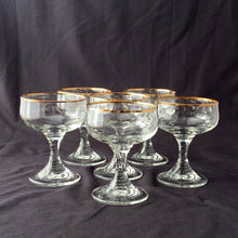 Load image into Gallery viewer, A stunning set of six elegant stemmed clear crystal champagne or sherbet glasses. Each bowl is rimmed and banded in 24 carat gold. Perfect for entertaining with a touch of elegance...cheers!  All are in excellent  condition with no scratches, chips, or cracks. Maker unknown.  Each glass measures 3 3/4 x 4 3/4 inches
