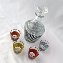 Load image into Gallery viewer, This mid-century vintage decanter and four shot glass set is so retro! The houndstooth pattern is vibrant and quite the conversation piece. What a fun set for a casual vintage vibe.  All pieces are in excellent condition, free from chips or cracks. Marked &quot;FRANCE&quot; on the bottom. Made by Cristal D&#39;arques in the 1950s.  The decanter measures 3 x 6 1/2 inches and the shot glasses 1 1/2 x 2 inches
