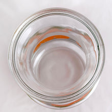 Load image into Gallery viewer, Bring a little sunshine to table with this retro glass carafe decorated with vibrant oranges and white flowers. Produced by Anchor Hocking Glass Company USA. Production began on this pattern in 1950s. This piece was manufactured in 1987. This carafe or pitcher is perfect for juice, iced tea, lemonade, water or mix up some cocktails!  In excellent condition, no chips or cracks and the colour is vibrant orange and green.  Measures 4 x 8 5/8 inches
