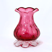 Load image into Gallery viewer, Beautiful, heavy-weighted cranberry glass vase with clear scalloped foot. The vase has an urn-shape with a ribbed detail and ruffled edge. A very nice piece of glass to use for a floral bouquet or repurpose to fold make-up brushes or q-tips. We see a lot of these pieces attributed to Pilgrim Glass, but without a maker&#39;s mark we can&#39;t be certain.  In excellent condition, free from chips/cracks/repairs.  Measures 2 7/8 x 4 inches
