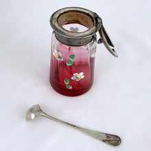 Load image into Gallery viewer, Antique cranberry glass silver lidded condiment jar, hand painted with enamel flowers. Maker unknown. Sterling silver ladle or spoon made in Birmingham England.   The jar is in good vintage condition. Glass is free from chips/cracks and the lid has an aged patina. The spoon is in excellent condition, in as found condition.  Jar measures 1 7/8 x 3 1/2 inches  Spoon measures 3-1/2&quot;
