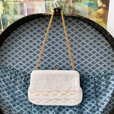 Stunning mid-century vintage evening bag covered in cream coloured seed and bugle beads in a lovely floral pattern with gold toned metal kiss clasp and chain strap (we don't believe is original) which can be used at two different lengths. The interior is lined with cream coloured satin and has a small pocket. The bag is large enough for a small cell phone, credit cards/cash, compact/lipstick. Produced in Korea. In overall excellent condition with minor wear to the clasp and interior satin.