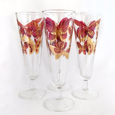 Indulge in elegance with this exquisite set of four vintage mid-century pilsner champagne glasses, adorned with vibrant dark pink butterflies and luxurious 22kt gold on clear glass. Designed by Fred Press, Federal Glass blank, USA, 1950s. Whether sipping on a refreshing beer or toasting with a glass of bubbly champagne, these glasses will elevate your barware with high glamour!


In excellent condition, no chips or wear.

Measures 2 7/8 x 8 3/8 inches

Capacity of 10 ounces