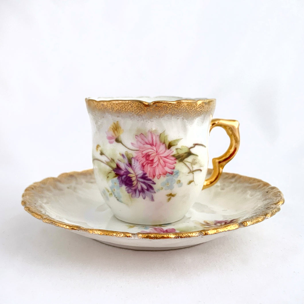 Pretty vintage white porcelain demitasse cup and saucer beautifully hand painted with pink and purple aster flowers with gold gilt on the rims and handle. Unmarked.  In excellent condition, free from chips/cracks/repairs.  Dimensions of cup 2