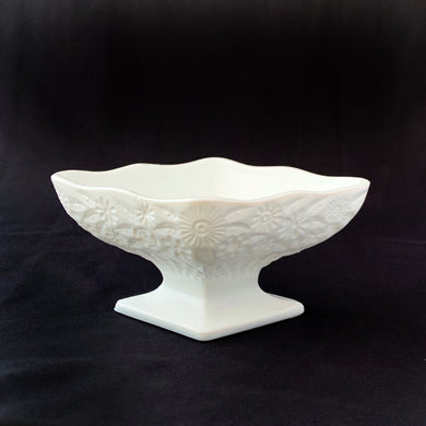 Diamond-shaped footed pedestal dish is embellished with pressed glass floral details, a diamond starburst on the bottom of the bowl and a lovely scalloped edge. It's such a sweet piece that will look great in any space. Produced by the Indiana Glass Company, circa 1940.  In excellent condition, free from chips and cracks.  Measures 6 1/2 x 4 1/2 x 3 inches