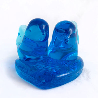 This lovely hand blown azure blue art glass pair of bluebirds perched on a heart was created by artisan Leo Ward in 1992. Mr. Ward was the creator of Arkansas' Bluebird of Happiness and owner of Terra Studios in Arkansas. He passed away at 89 years young in 2017.  This piece is in excellent condition, free from chips or cracks. Measures 4