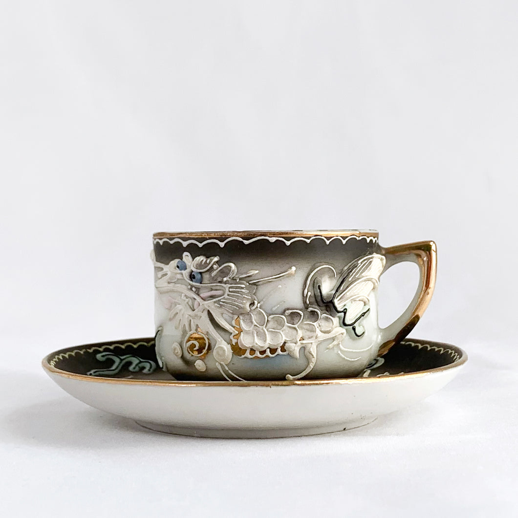 Vintage slip-glazed moriage, hand painted Dragonware espresso or child's porcelain cup and saucer with gold detail on the handle and rim. Marked 