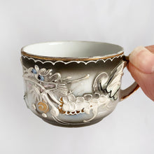 Load image into Gallery viewer, Vintage slip-glazed moriage, hand painted Dragonware espresso or child&#39;s porcelain cup and saucer with gold detail on the handle and rim. Marked &quot;HAND PAINTED BETSONS, circa 1950. The artistry of this piece is stunning!  In excellent condition, free from chips/cracks.  Cup measures 2&quot; x 1-1/2&quot; and saucer measures 3-3/4&quot;
