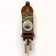 Load image into Gallery viewer, Vintage folklore wood wall clock with brass scrollwork, brass Atlas holding a black globe above its head, decorated with the moon and stars. The clock dial has with roman numerals, numbers and decorative elements in black with central hand painted scene of the sea with two sailing ships, above the dial is a pastoral scene and below folk art florals. Eight day movement with chime striking on the hour and every half hour. Brass weights, pendulum and chains included. Warmink WUBA, Netherlands, circa 1960s.
