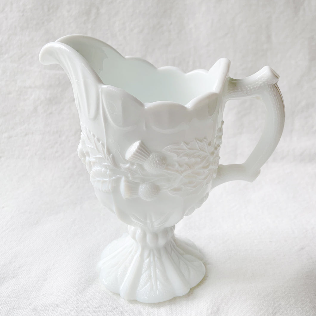 This elegant EAPG milk glass creamer pitcher has incredible detail including Scottish thistles, Irish clover and English roses with a stylized foot, a twig style D-shaped handle and a detailed graduated scalloped edge. We believe this was created by the Indiana Glass Co., but cannot confirm. It's quite a striking and elegant piece!  In excellent condition. No chips or cracks. Unmarked.  Measures 4-1/2