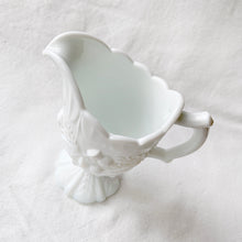 Load image into Gallery viewer, This elegant EAPG milk glass creamer pitcher has incredible detail including Scottish thistles, Irish clover and English roses with a stylized foot, a twig style D-shaped handle and a detailed graduated scalloped edge. We believe this was created by the Indiana Glass Co., but cannot confirm. It&#39;s quite a striking and elegant piece!  In excellent condition. No chips or cracks. Unmarked.  Measures 4-1/2&quot; x 5&quot; (incl. handle)
