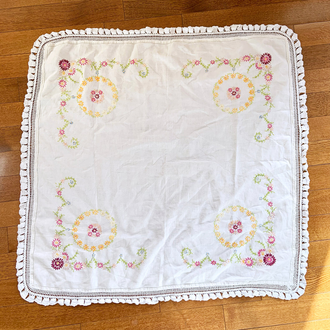 Lovely vintage ecru/off-white square linen tablecloth. Each corner of the tablecloth is  hand embroidered with a colourful floral motif in shades of pink, yellow, blue, purple and green and the perimeter has an intricate white crochet border. Use as intended or repurpose the border or embroidery in other projects.  In great vintage condition, free from tears or stains.  Measures 38-1/2