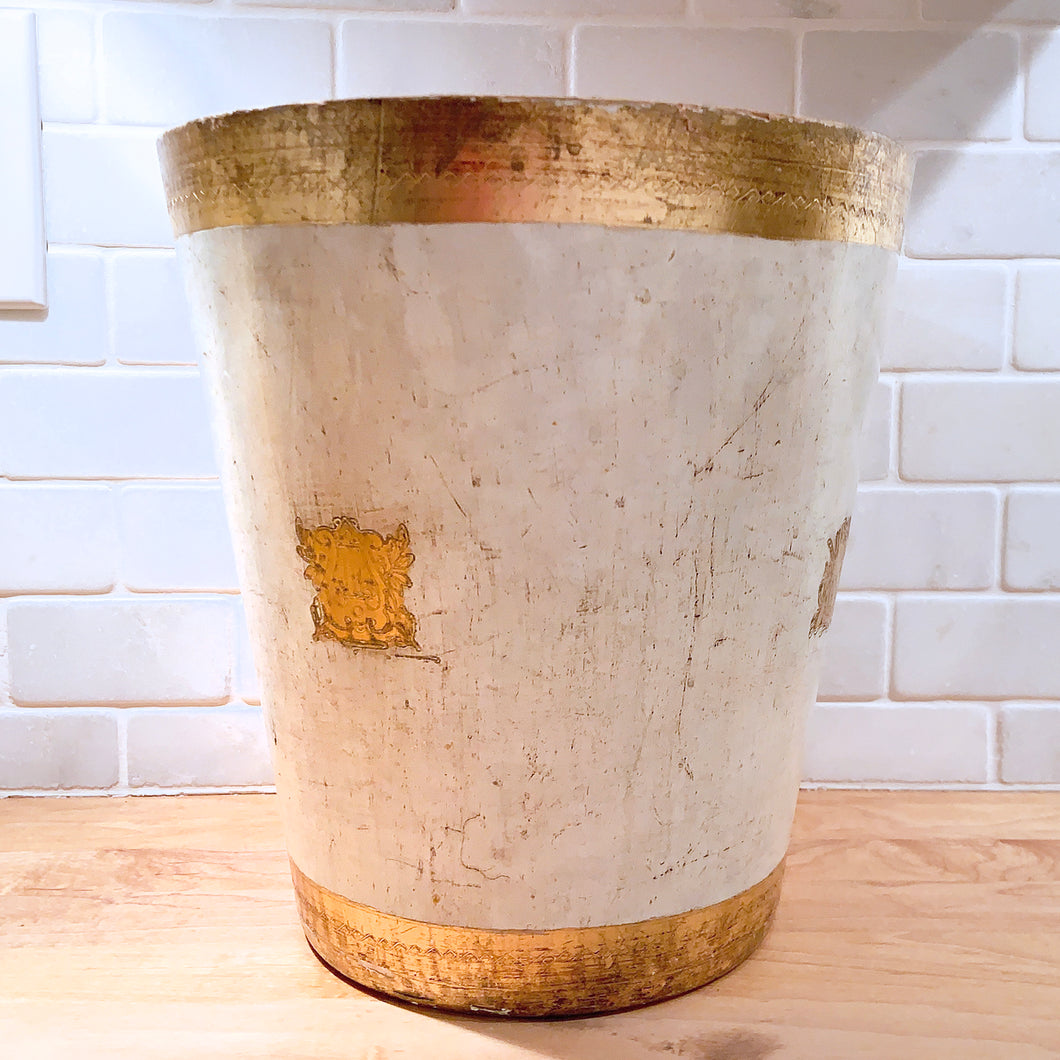 A vintage Florentine waste basket, beautifully hand painted in cream with gold gilt design. Made in Italy, circa 1960s.  In as found vintage condition. Top rim is worn.  Measures 9 3/4 x 10 3/4 inches