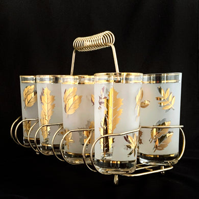 Set of eight mid-century vintage Golden Foliage highball glasses in brass carrying caddy with spiral handle.  Produced by the Libbey Glass Company between 1953 - 1978. These glasses will elevate any bar cart and are perfect for any occasion or cocktail! Great vintage condition. The glasses are free from chips/cracks. Minor wear present to the gold on the rim. Each glass measures 2-3/4