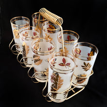 Load image into Gallery viewer, Set of eight mid-century vintage Golden Foliage highball glasses in brass carrying caddy with spiral handle.  Produced by the Libbey Glass Company between 1953 - 1978. These glasses will elevate any bar cart and are perfect for any occasion or cocktail! Great vintage condition. The glasses are free from chips/cracks. Minor wear present to the gold on the rim. Each glass measures 2-3/4&quot; x 5-1/2&quot; (12oz)
