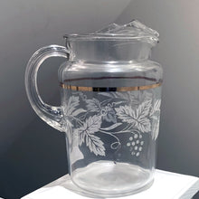 Load image into Gallery viewer, This large vintage pressed glass pitcher is perfect for water, lemonade, ice tea, beer or the bevvy of your choosing. It has an textured pattern of grapevines and a gold band, it has that handy ice lip too. Retro 1970s  In excellent condition, no chips or cracks.  Measures 5 3/4 x 9 inches  Capacity 64 ounces
