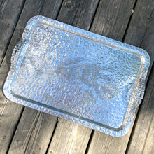 Load image into Gallery viewer, One of the pretties pieces of hammered aluminum we&#39;ve encountered! This sweet serving tray has decorative ribbon style handles detailed with floral details and embossed tulips on the tray surface (shape 423). Made by Rodney Kent, circa 1950. A great addition to your serveware or bar cart.  In excellent condition. Manufacturer&#39;s marks on the bottom.  Measures 18&quot; x 13&quot;
