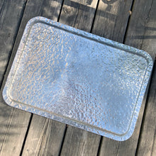 Load image into Gallery viewer, One of the pretties pieces of hammered aluminum we&#39;ve encountered! This sweet serving tray has decorative ribbon style handles detailed with floral details and embossed tulips on the tray surface (shape 408). Made by Rodney Kent, circa 1950. A great addition to your serveware or bar cart.  In excellent condition. Manufacturer&#39;s marks on the bottom.  Measures 20 x 14&quot;

