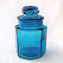 Load image into Gallery viewer, This vintage sky blue apothecary jar is perfect to store dry goods, bath accessories or as a beautiful display piece. Great hexagonal shape with a daisy on the top of the ground stopper. Takahashi Glass, Japan, circa 1970.  In excellent condition, no chips or cracks.  Measures 3 1/2 x 5 1/2 inches
