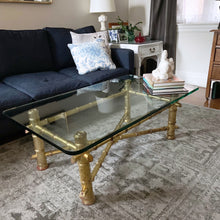 Load image into Gallery viewer, Stunning authentic Hollywood Regency faux bamboo coffee table. The table features a sturdy wood frame with half inch thick glass top. The base has a unique decorative finish which lends itself to either a glam or boho decor style. Its petite size makes it the perfect choice for a small space while adding incredible impact. The table base in excellent vintage condition with minor wear and the one inch thick glass top is free from chips. Measures 42 x 24 x 16-1/2 inches
