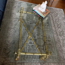 Load image into Gallery viewer, Stunning authentic Hollywood Regency faux bamboo coffee table. The table features a sturdy wood frame with half inch thick glass top. The base has a unique decorative finish which lends itself to either a glam or boho decor style. Its petite size makes it the perfect choice for a small space while adding incredible impact. The table base in excellent vintage condition with minor wear and the one inch thick glass top is free from chips. Measures 42 x 24 x 16-1/2 inches
