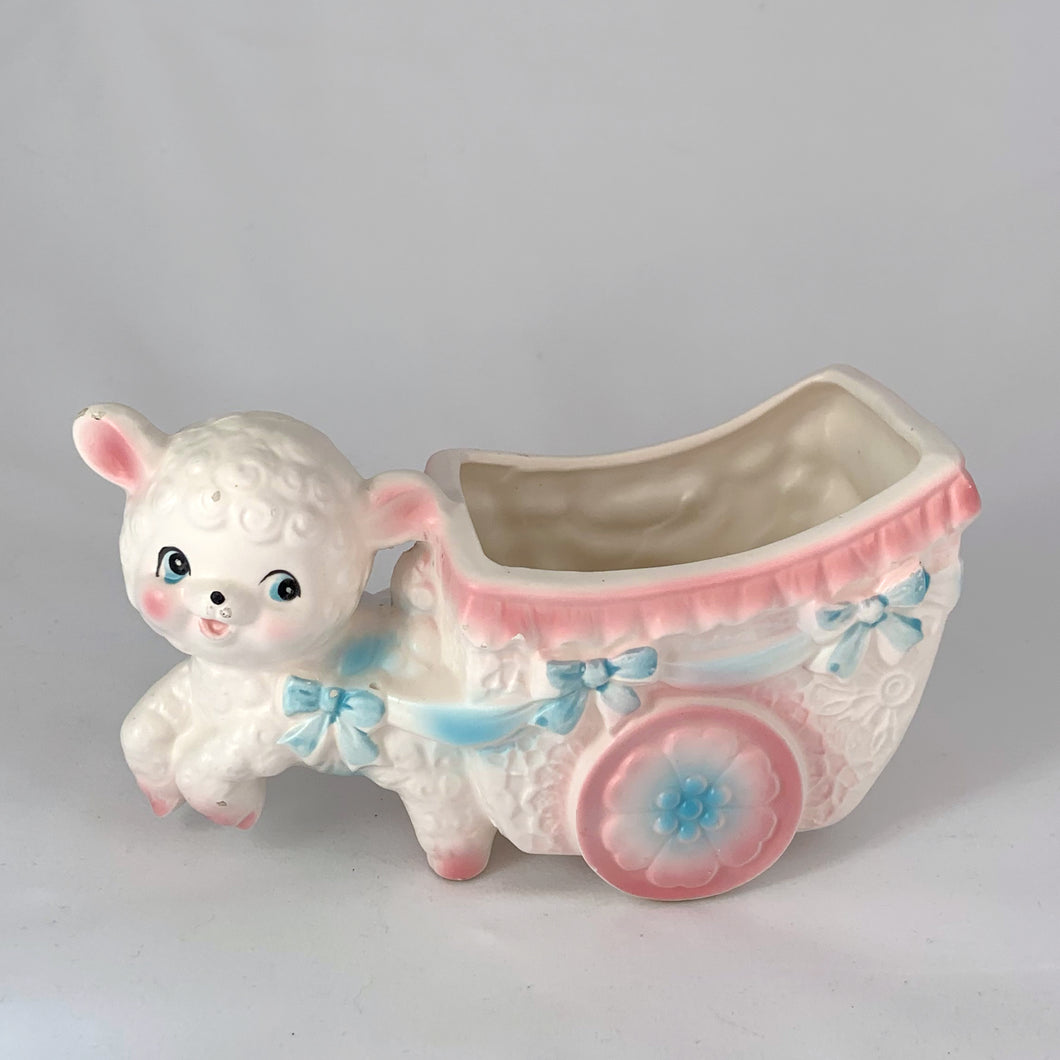 kitsch adorable vintage mid-century ceramic planter of a sweet little lamb pulling a baby carriage pram with ribbons and flowers in pink and blue on a white. It’s perfect for a tiny houseplant/succulent or repurpose to hold for baby lotions/accessories, pens or make-up brushes. Easter gift fill with chocolate eggs. Made by Inarco in Japan, shape E5432. Good vintage condition, no chips/cracks/repairs, some glaze loss on one ear (see photos). Measures 6 3/4 x 3 x  3 3/4 inches