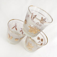 Load image into Gallery viewer, We are addicted to mid century style barware and this whiskey cocktail glass is gorgeous! Produced by the Libbey Glass Co. in the USA, circa 1960s. It is clear glass with a gold band on either side of a frosted band and decorated with gold maple leaves and maple keys. These glasses were literally is everyone&#39;s rec rooms in the 60s and 70s!  Measures 3 1/4 x 3 1/4 inches
