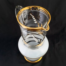 Load image into Gallery viewer, Vintage blown glass pitcher beautifully detailed with white Lily-of-the-Valley with gold leaves along with soft white and gold bands and applied blown glass handle. The perfect piece of serveware for spring and summer gatherings! Produced in Romania, circa 1950s.  In excellent condition, free from chips/cracks/wear.  Measures 5 x 11 1/8 inches
