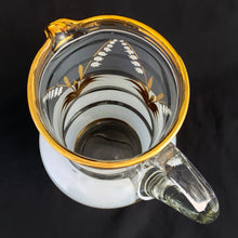 Load image into Gallery viewer, Vintage blown glass pitcher beautifully detailed with white Lily-of-the-Valley with gold leaves along with soft white and gold bands and applied blown glass handle. The perfect piece of serveware for spring and summer gatherings! Produced in Romania, circa 1950s.  In excellent condition, free from chips/cracks/wear.  Measures 5 x 11 1/8 inches
