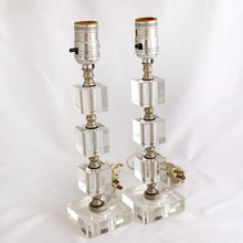 Load image into Gallery viewer, This is a beautiful pair of matching vintage clear lucite lamps featuring squares base and cubes with silver spacers. Perfect for a bedside lighting, or as accent lighting inon a console table. Circa 1950s.
