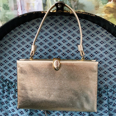 Stunning mid-century vintage gold lamé evening bag with gold toned oval button flip clasp, top strap handle and the interior is lined with gold satin. The bag is large enough for a cell phone, credit cards/cash, small compact/lipstick. Crafted by After Five, USA, 1950s. Adds a dash of Hollywood glam to your fashion statement!

In vintage condition with age-related wear. Maker's mark on the interior.

Measures 7 3/4 x 1 x 5 inches, 5 1/8 inch handle drop