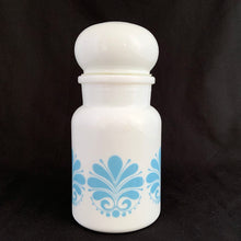 Load image into Gallery viewer, This vintage milk glass apothecary jar decorated with a blue geometric floral pattern topped off with a bubble-shaped lid. Could be used as a kitchen canister, bathroom apothecary jar or as a beautiful display piece. It has a plastic piece that makes a great seal if using for food storage. Marked on the bottom &quot;Container Made in Belgium&quot;, circa 1970.  In excellent condition, no chips or cracks.  Measures 3 1/2 x 7 inches
