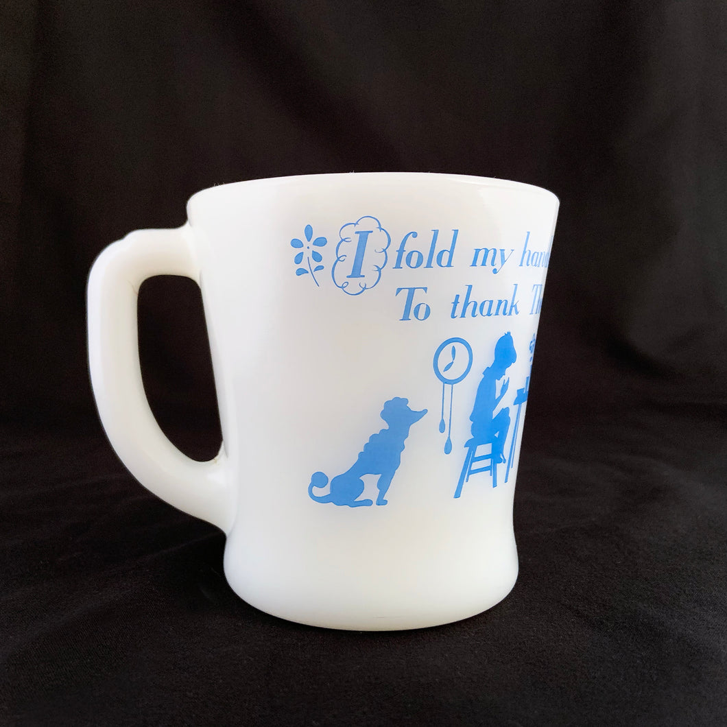 Vintage Fire-King milk glass D-handled mug printed in blue with seated children saying mealtime prayer while their mom serves them with puppy and bird observing. The prayer reads, 